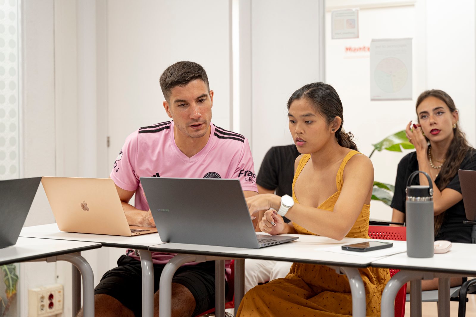Two students look at a laptop in the classroom